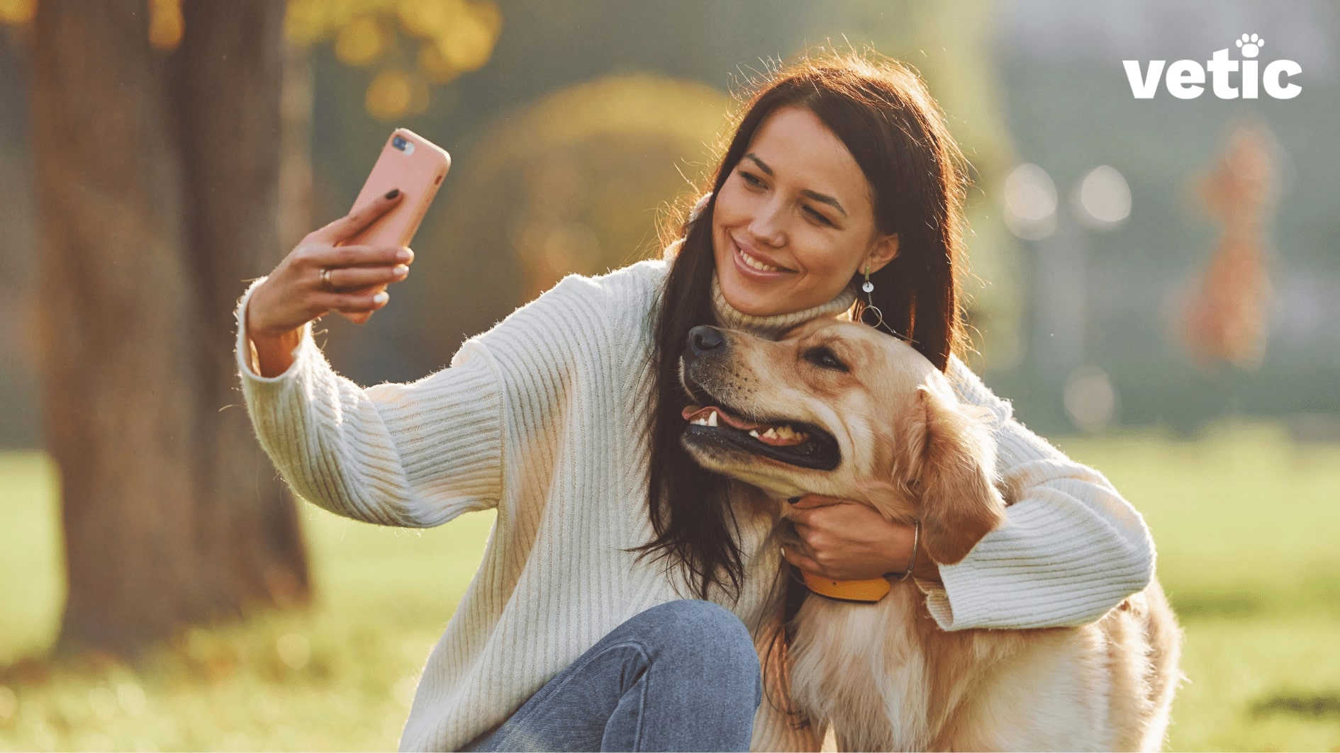 Woman at the park taking a selfie with her golden retriever