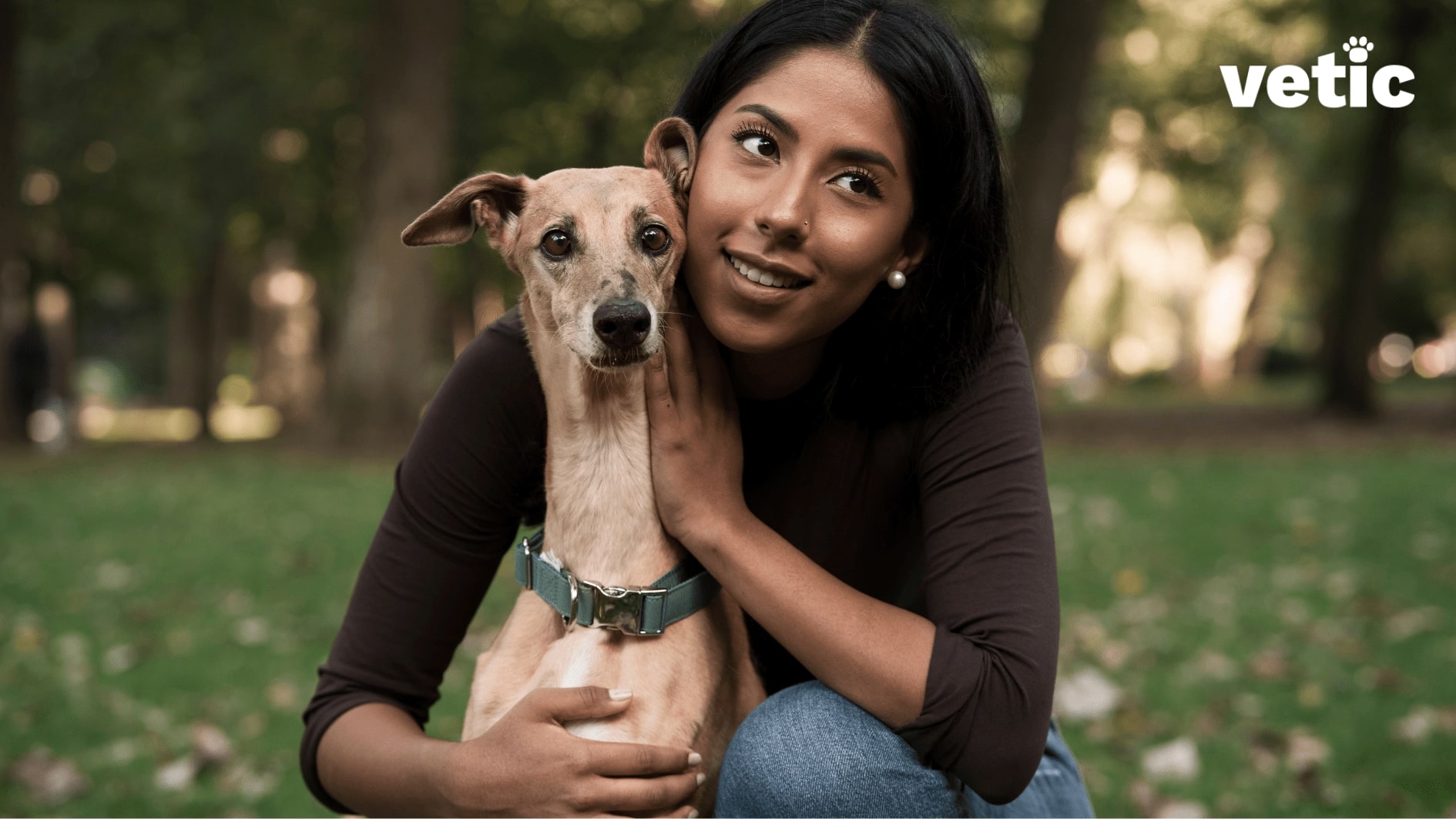 Woman at the park hugging her whippet